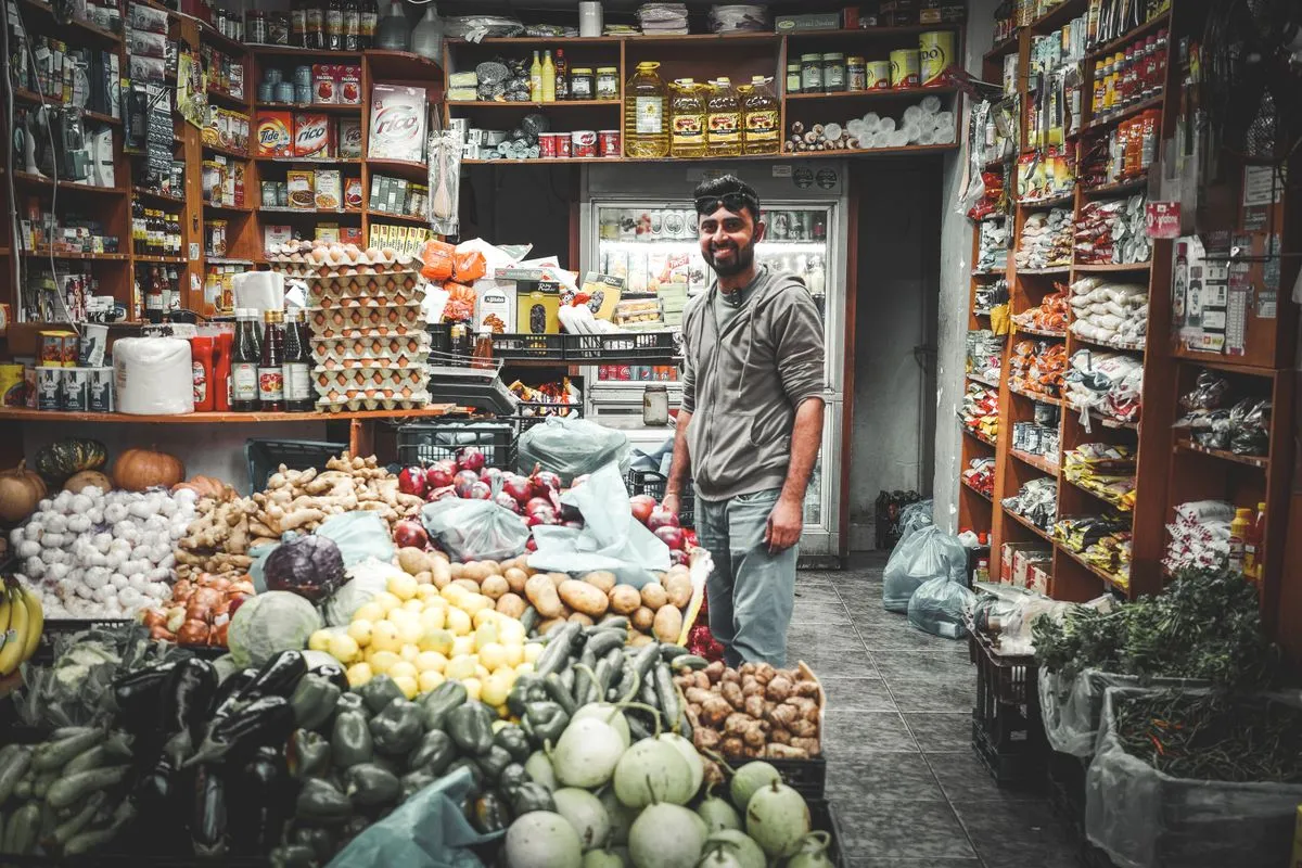Een lachende groenteboer tussen zijn uitgestalde groente en fruit